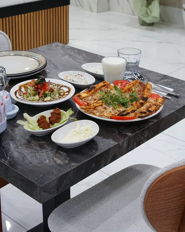 Pide, salata, meze, çiğ köfte ve ayranla kurulmuş masa